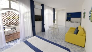 A modern hotel room with a bed, a yellow sofa, a dining table, and a kitchen area. - Palazzo San Giovanni (Scala)