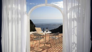 An outdoor seating area with a table and chairs, overlooking a body of water. - Palazzo San Giovanni (Scala)