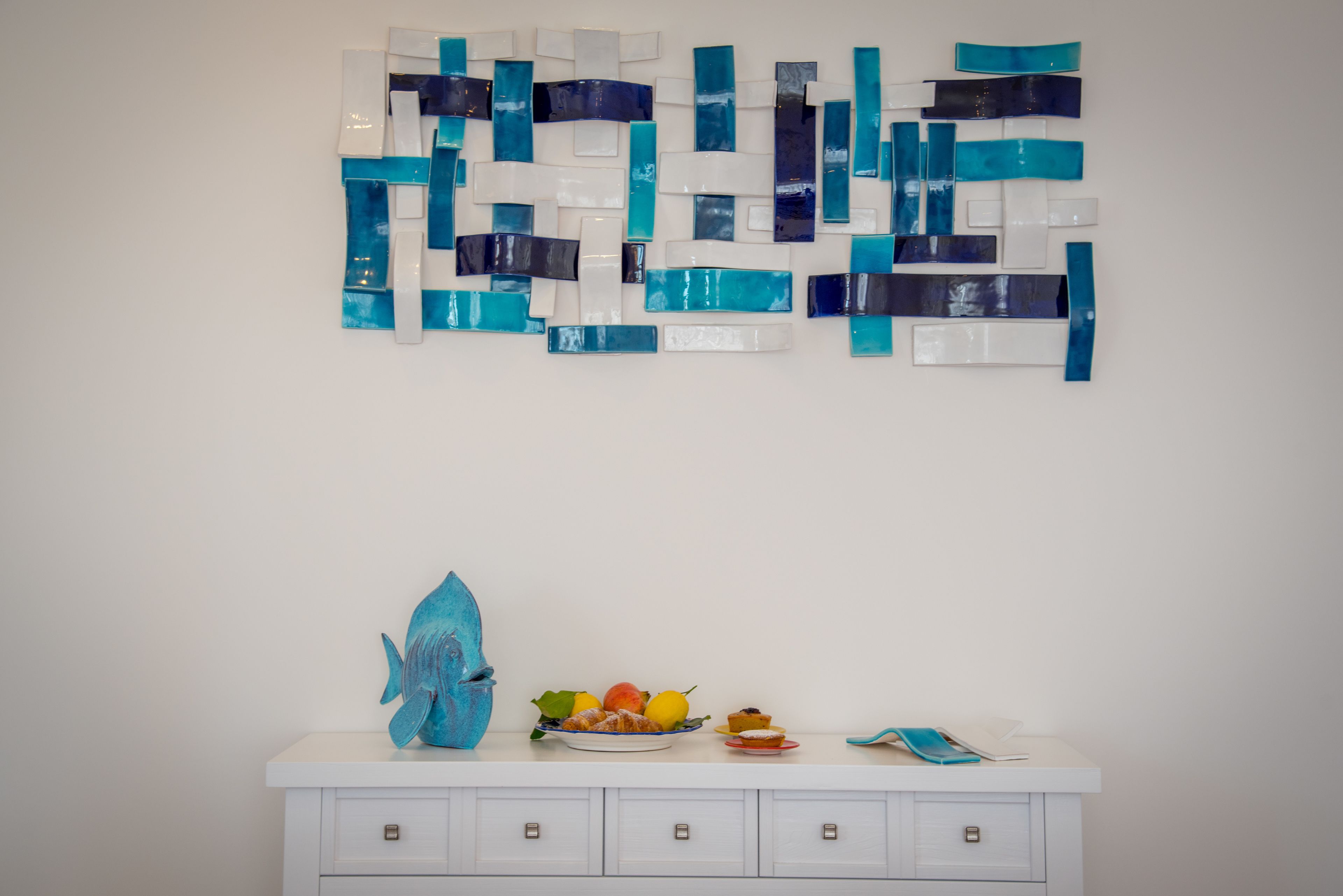 A white dresser with drawers and a blue fish sculpture on top.