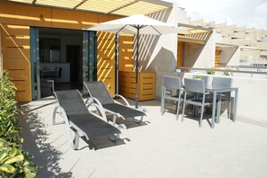 A rooftop terrace with two lounge chairs, a table, and an umbrella. - Vacation home on the beach, 2 bedrooms, 30 m² terrace. Beach 30 seconds (El Médano, Granadilla, Tenerife)