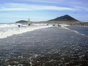 A beach with people engaging in windsurfing and kiteboarding. - Vacation home on the beach, 2 bedrooms, 30 m² terrace. Beach 30 seconds (El Médano, Granadilla, Tenerife)