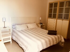 A neatly arranged bedroom with a bed, bedside tables, and a wardrobe. - Vacation home on the beach, 2 bedrooms, 30 m² terrace. Beach 30 seconds (El Médano, Granadilla, Tenerife)
