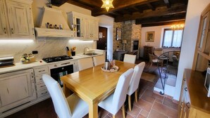 Una cocina con armarios blancos, una mesa de madera y sillas. Hay una lámpara en forma de estrella en el techo.