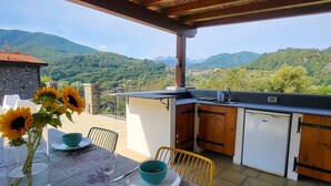 Una terraza con una mesa lista para comer, un fregadero y un refrigerador.