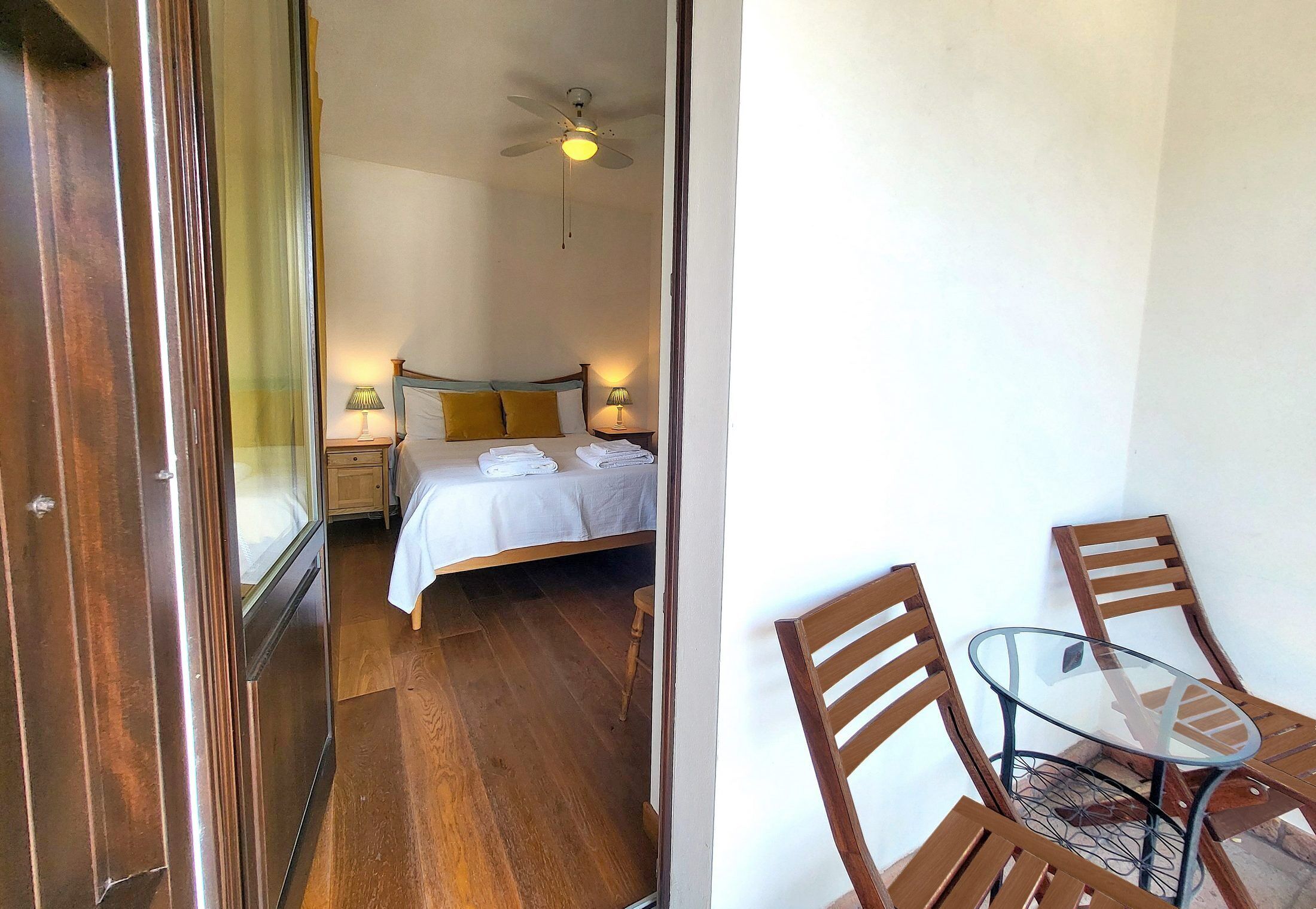 Une chambre à coucher avec un lit, des lampes de chevet, un ventilateur de plafond et un plancher en bois.