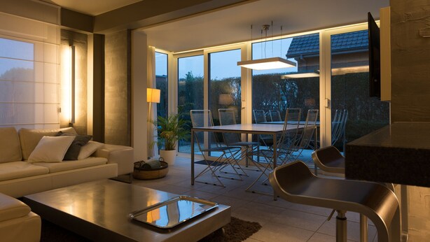 A modern living room with a sofa, coffee table, and dining area with chairs and a table.