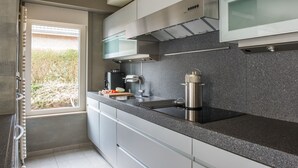 A modern kitchen with a stainless steel range hood, a built-in microwave, and a granite countertop.