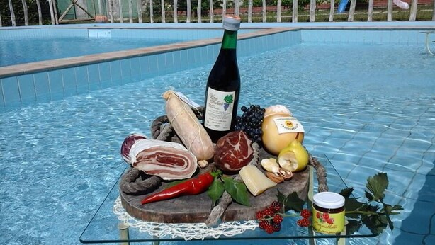 A poolside display of food and drink items including a bottle of wine, cheese, meats, and fruits. - Agriturismo Castanito (Vico Equense)