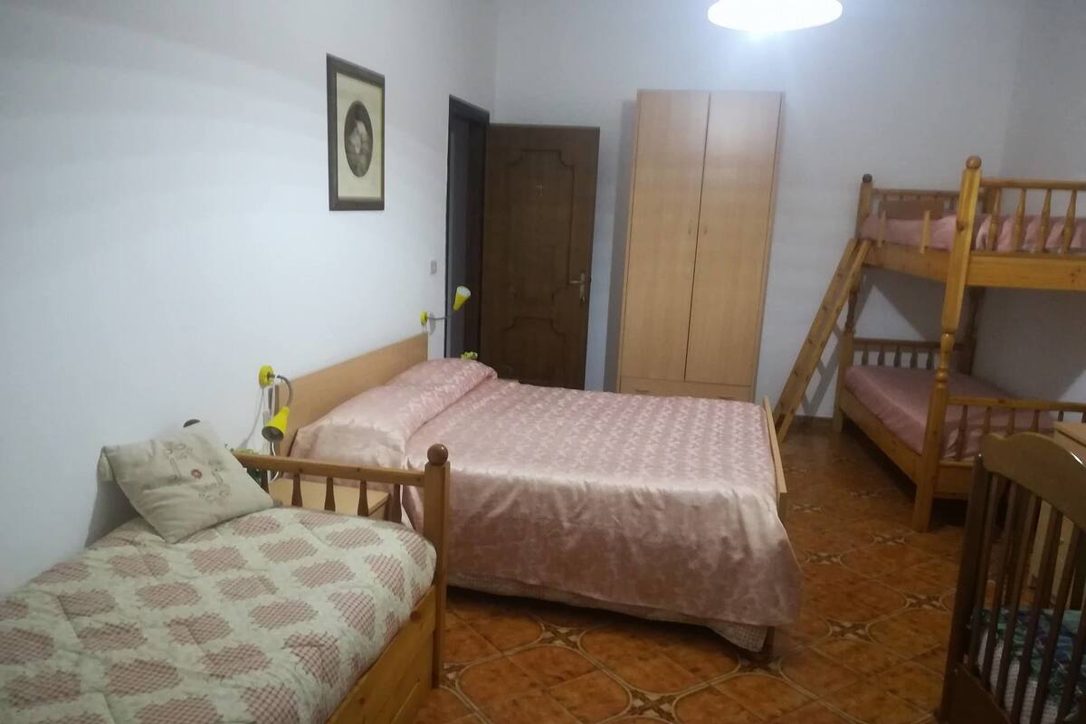 A bedroom with two single beds, a wardrobe, a bunk bed, and a door.