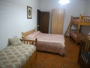 A bedroom with two single beds, a wardrobe, a bunk bed, and a door. - Agriturismo Castanito (Vico Equense)