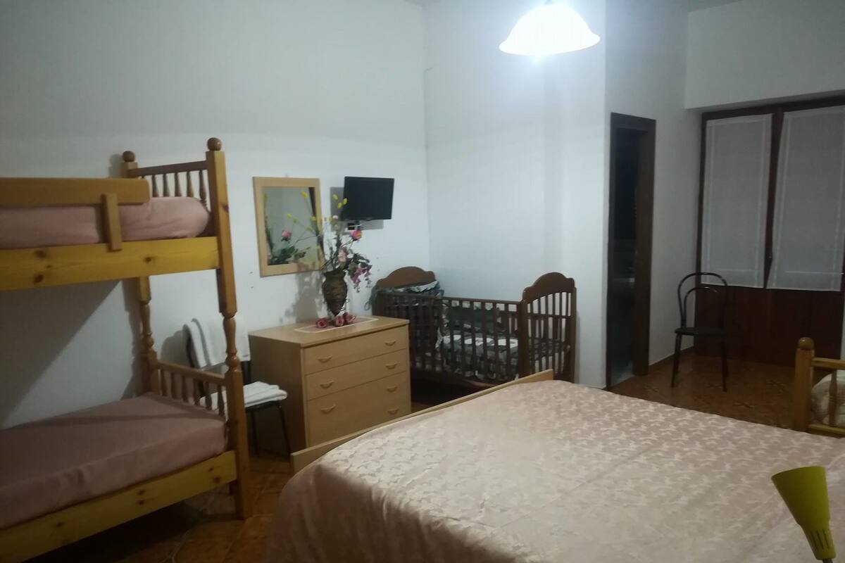A dormitory room with bunk beds, a desk, a chair, and a bed.