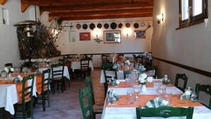 A restaurant with multiple tables and chairs, some with orange tablecloths. - Agriturismo Castanito (Vico Equense)