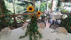 A table set for dining with a floral centerpiece, surrounded by chairs and a white tablecloth. - Agriturismo Castanito (Vico Equense)