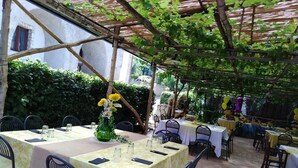 An outdoor dining area with tables set for guests, surrounded by greenery and a pergola structure. - Agriturismo Castanito (Vico Equense)