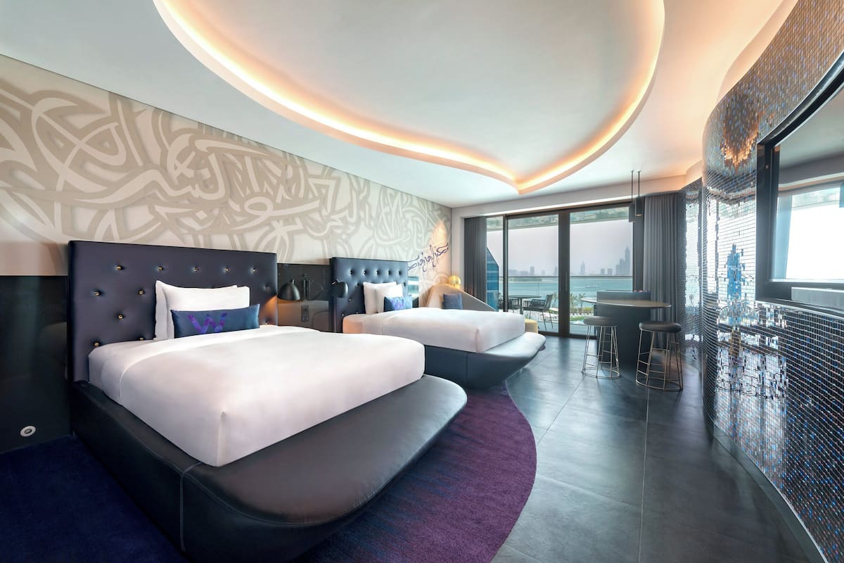 Een moderne hotelkamer met twee bedden, uitzicht over de stad en een barhoek.