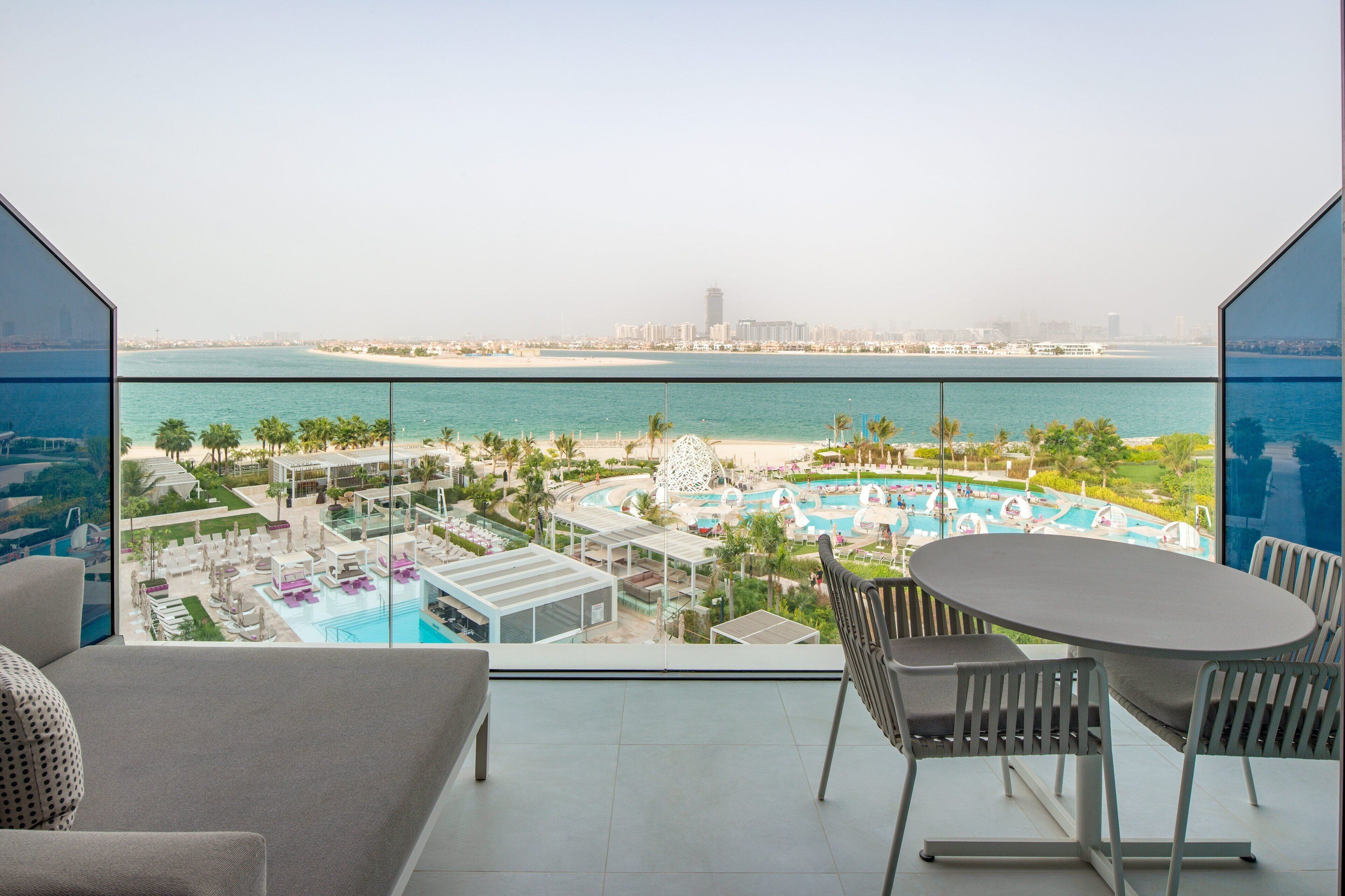 A balcony with a view of a beach resort, including a pool area and palm trees.