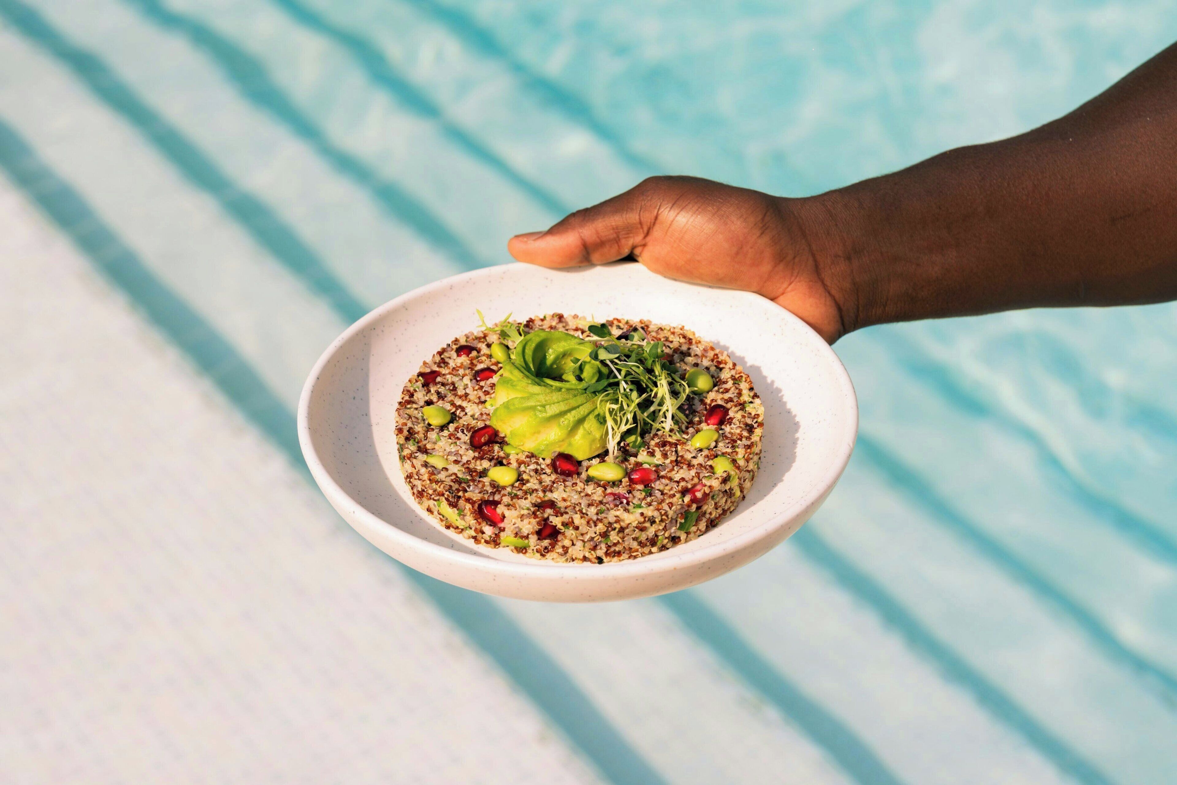 A bowl of food with a hand holding it.
