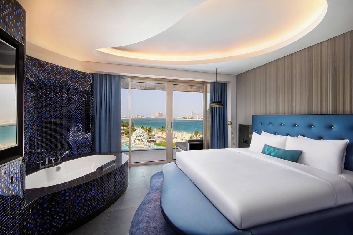 Een moderne hotelkamer met een groot bed, een badkuip en uitzicht op de oceaan.