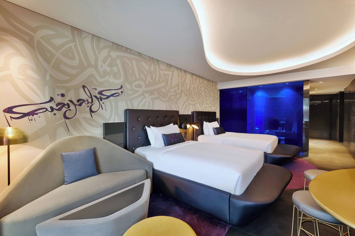 Een moderne hotelkamer met een groot bed, twee nachtkastjes, een sofa en een kleine tafel.