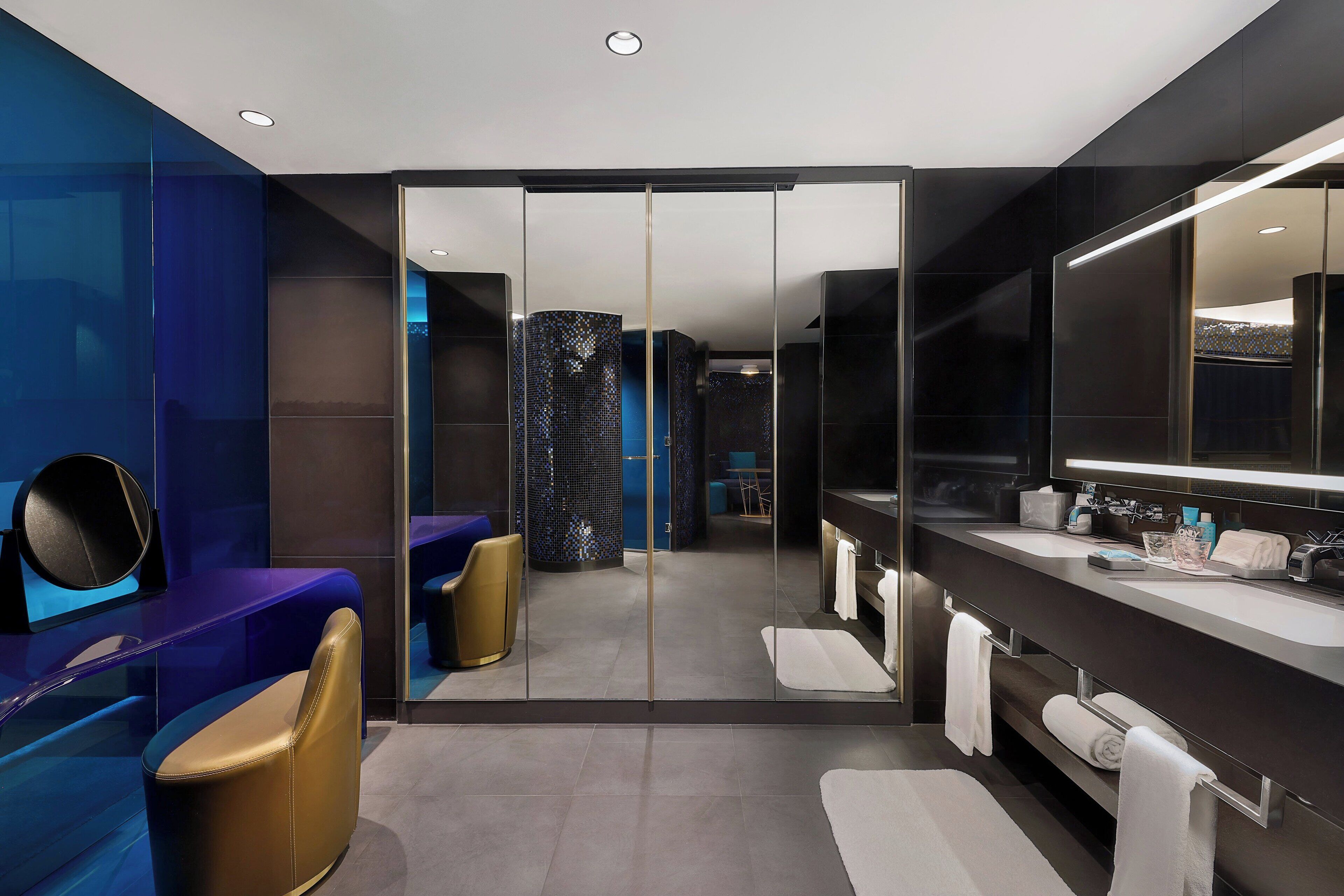 Un baño moderno con mampara de vidrio, lavamanos dobles y un espejo grande.