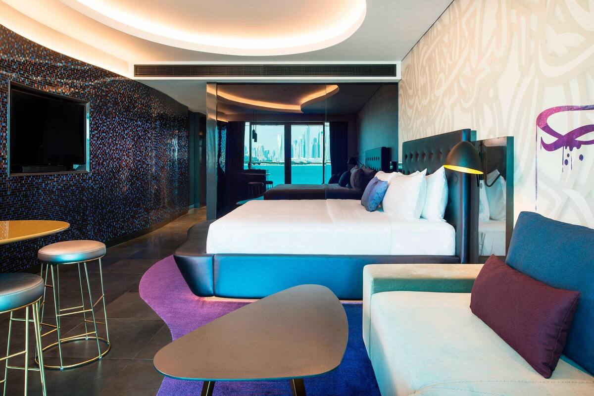 Een moderne hotelkamer met een groot bed, een zithoek en uitzicht op een stadsbeeld.