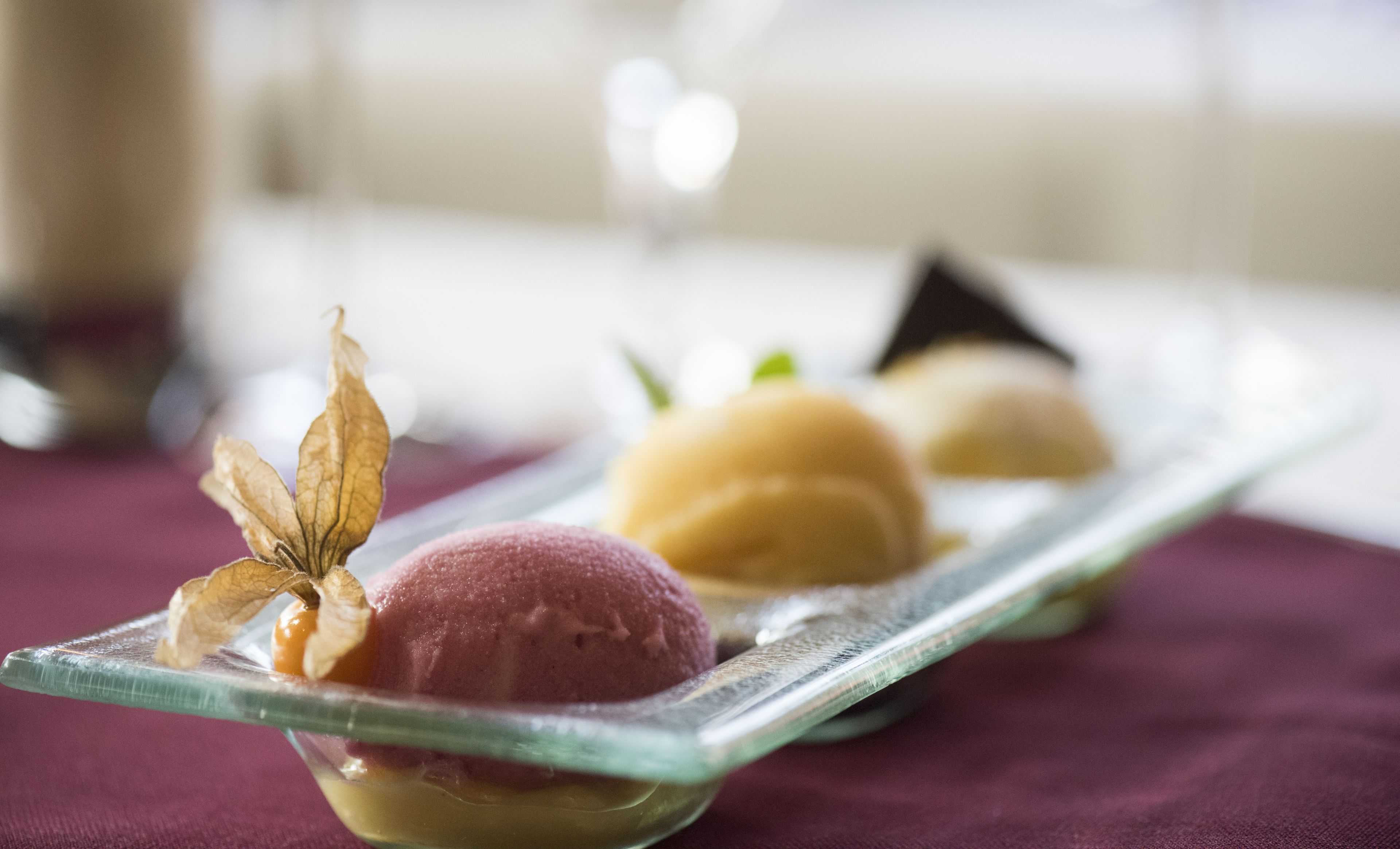 Un plato de postre con tres bolas de helado y una hoja decorativa.