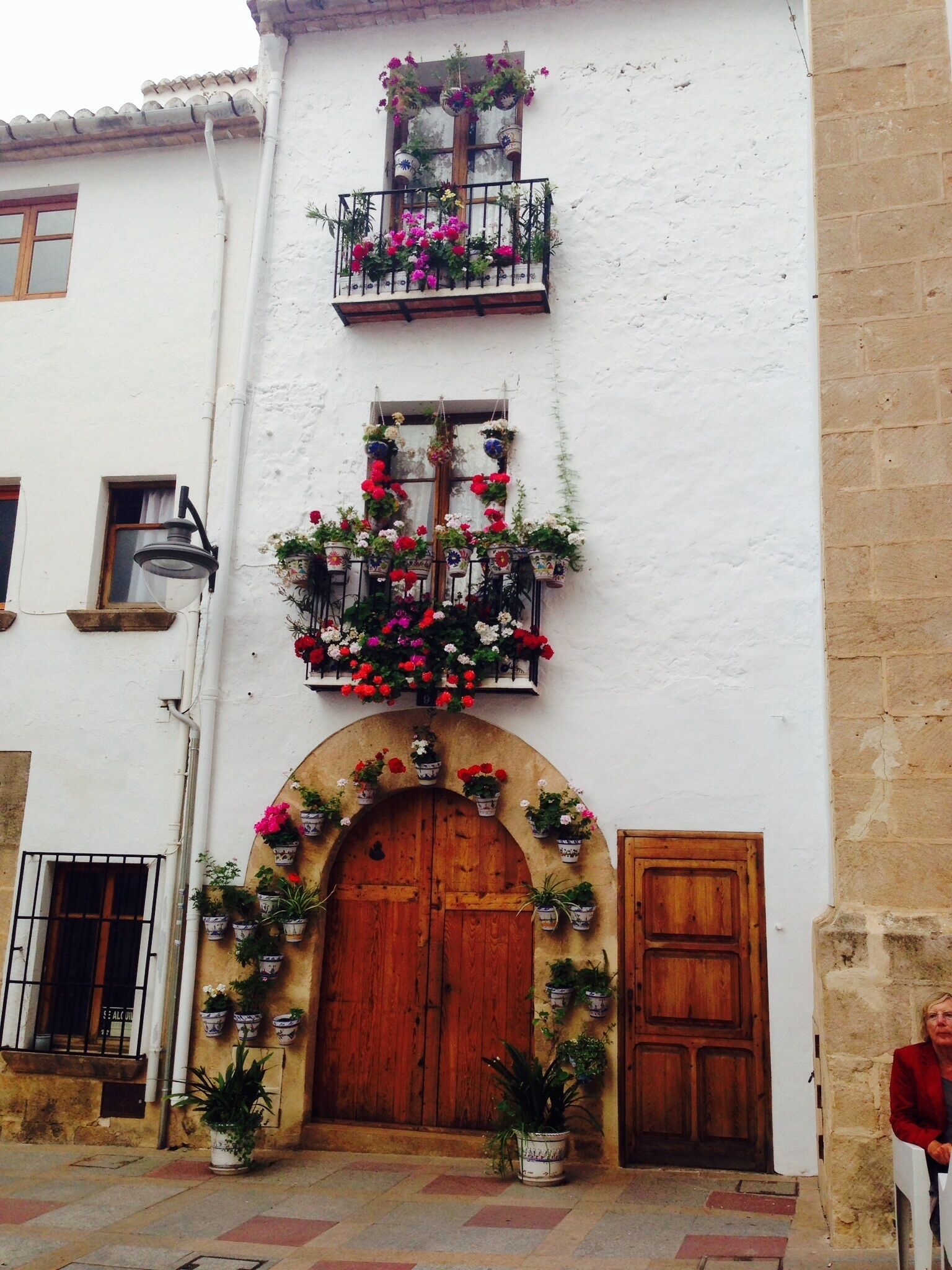Un edificio con puerta de madera, varias ventanas y balcones con macetas.