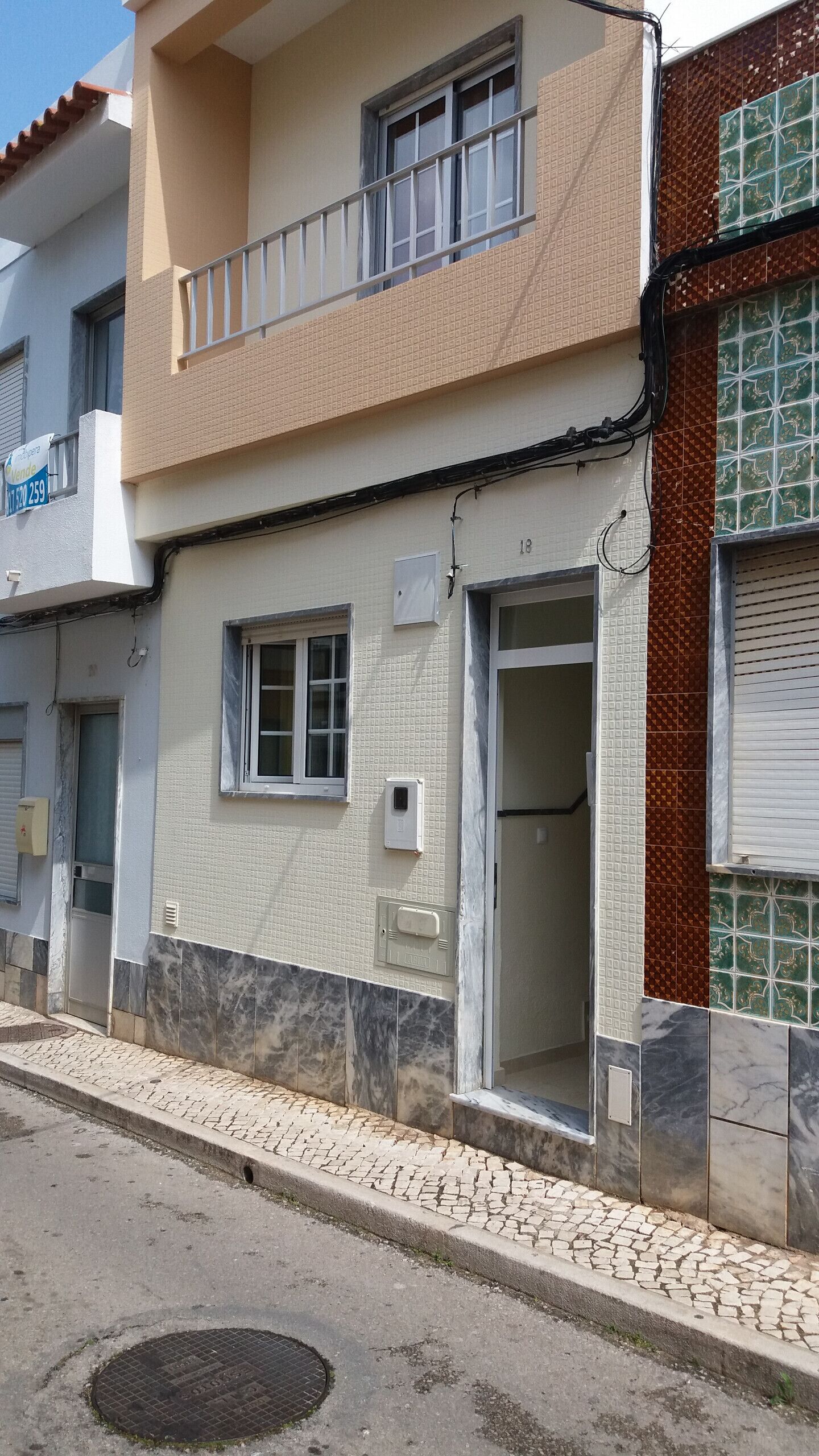 Un bâtiment à deux étages doté d’un balcon, d’une porte de garage et d’une façade recouverte de carreaux.