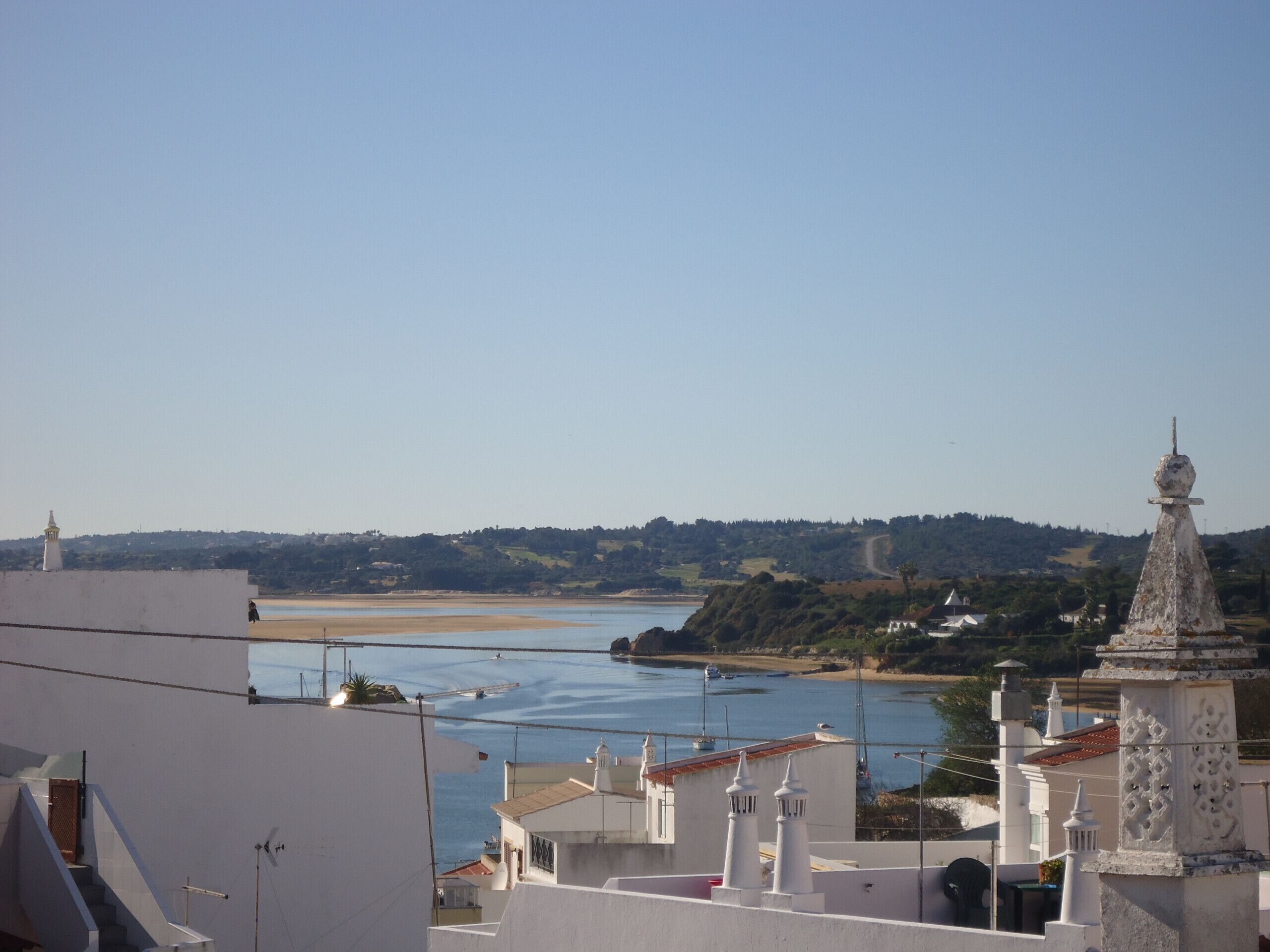 A coastal town with white buildings, a beach, and a clear sky.