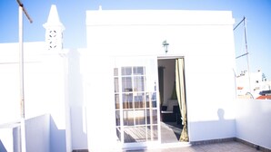 A white building with a tiled patio, a door, and a small window.