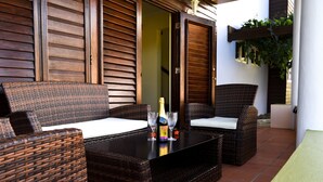 A wicker sofa set with a black table, two wine glasses, and a bottle of champagne. - Villa Cannelles (Micoud)