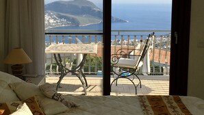 Un balcon avec une table et des chaises, donnant sur une ville côtière et la mer.