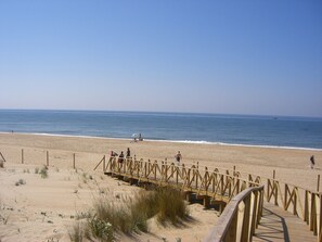A wooden boardwalk leading to a sandy beach with a clear view of the ocean. - Luxury villa with private pool overlooking golf course, close to beach (Cartaya (Huelva))