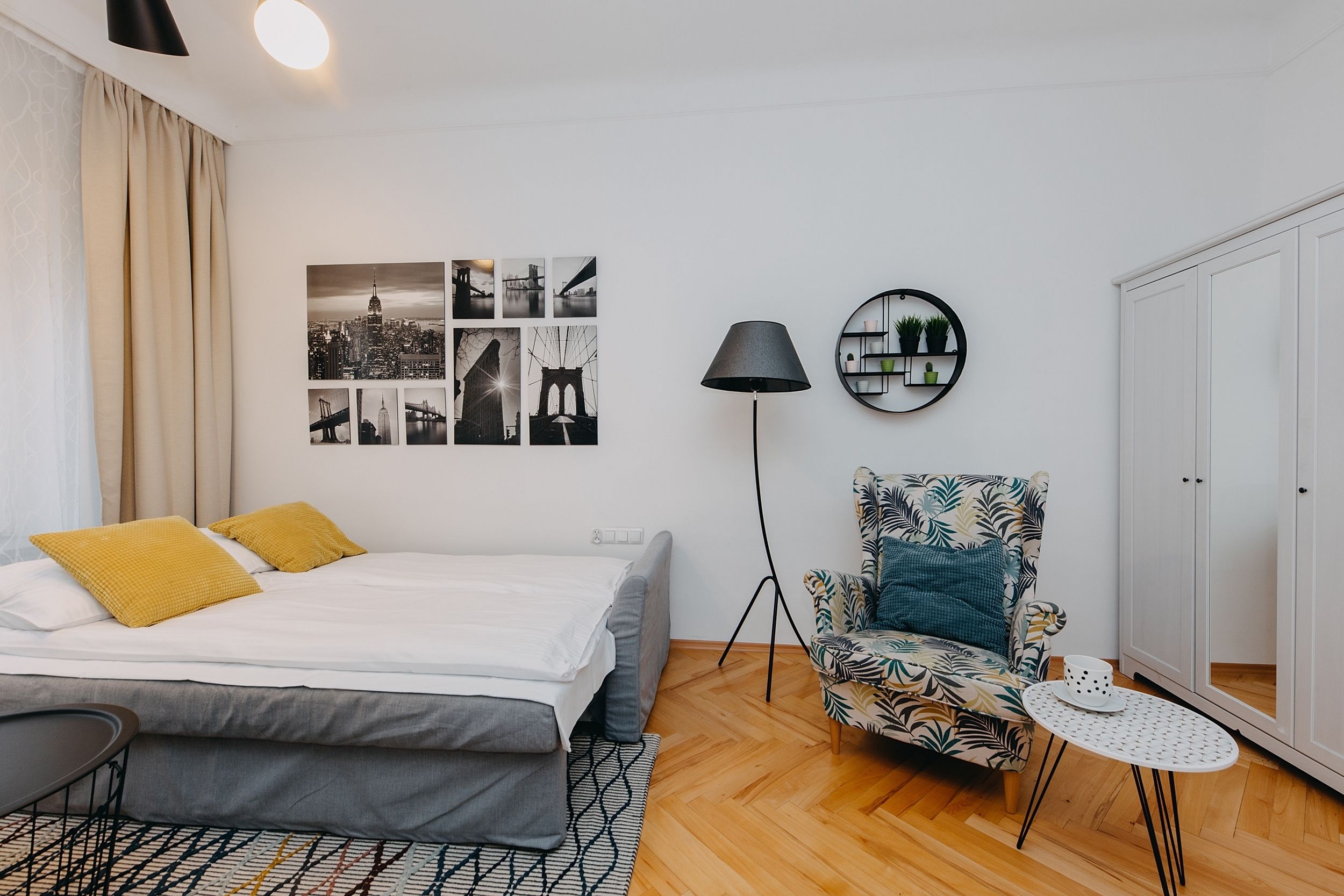 Een keurig opgemaakte slaapkamer met een bed, een stoel, een klein tafeltje en een lamp.