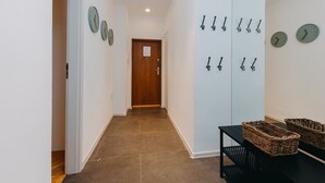 A hallway with a wooden door, a black table with baskets, and wall-mounted clocks. - ShortStayPoland Marszałkowska - B28 (Warsaw)