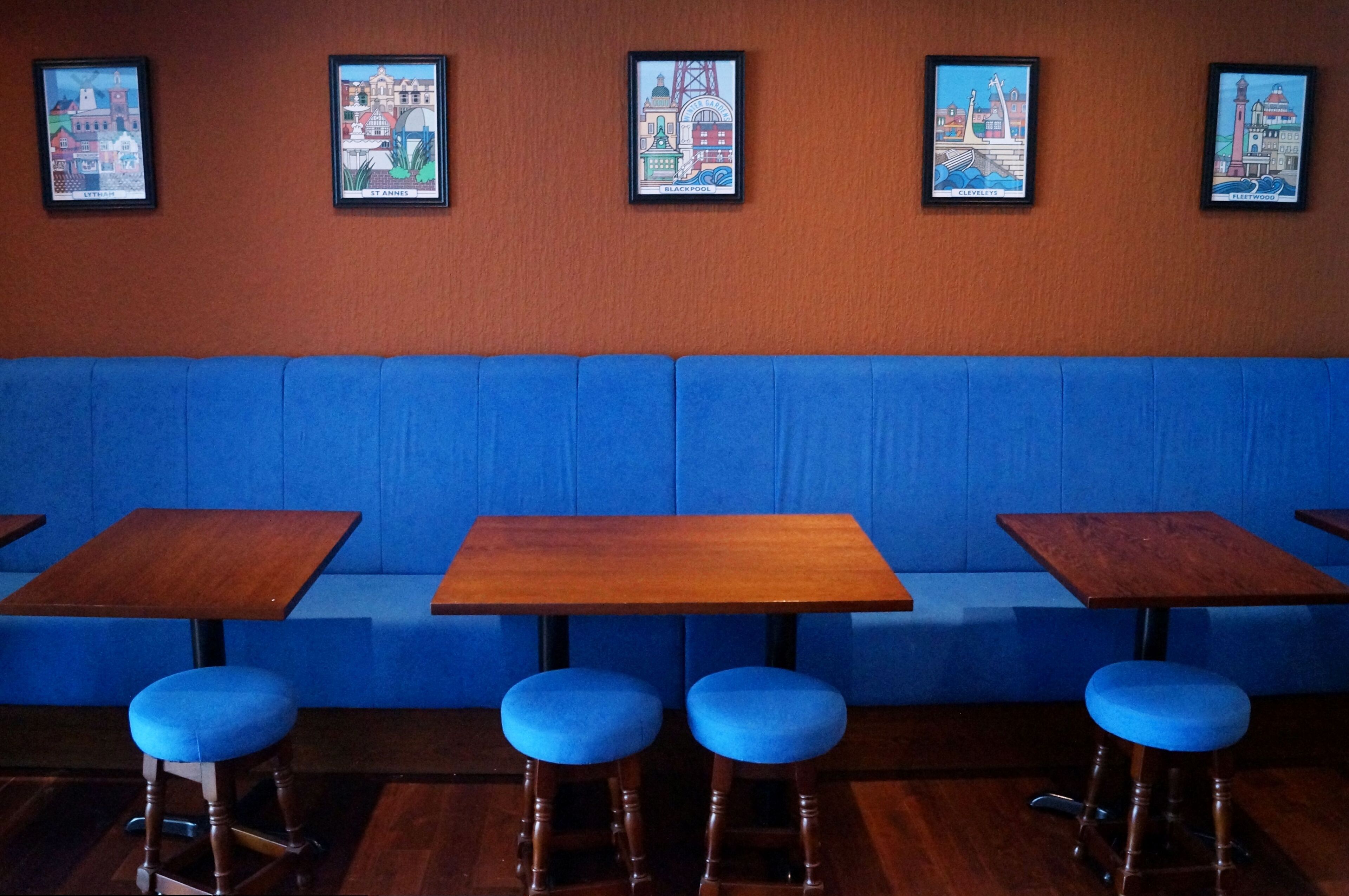 Un restaurante con asientos tipo cabina en azul y mesas de madera.