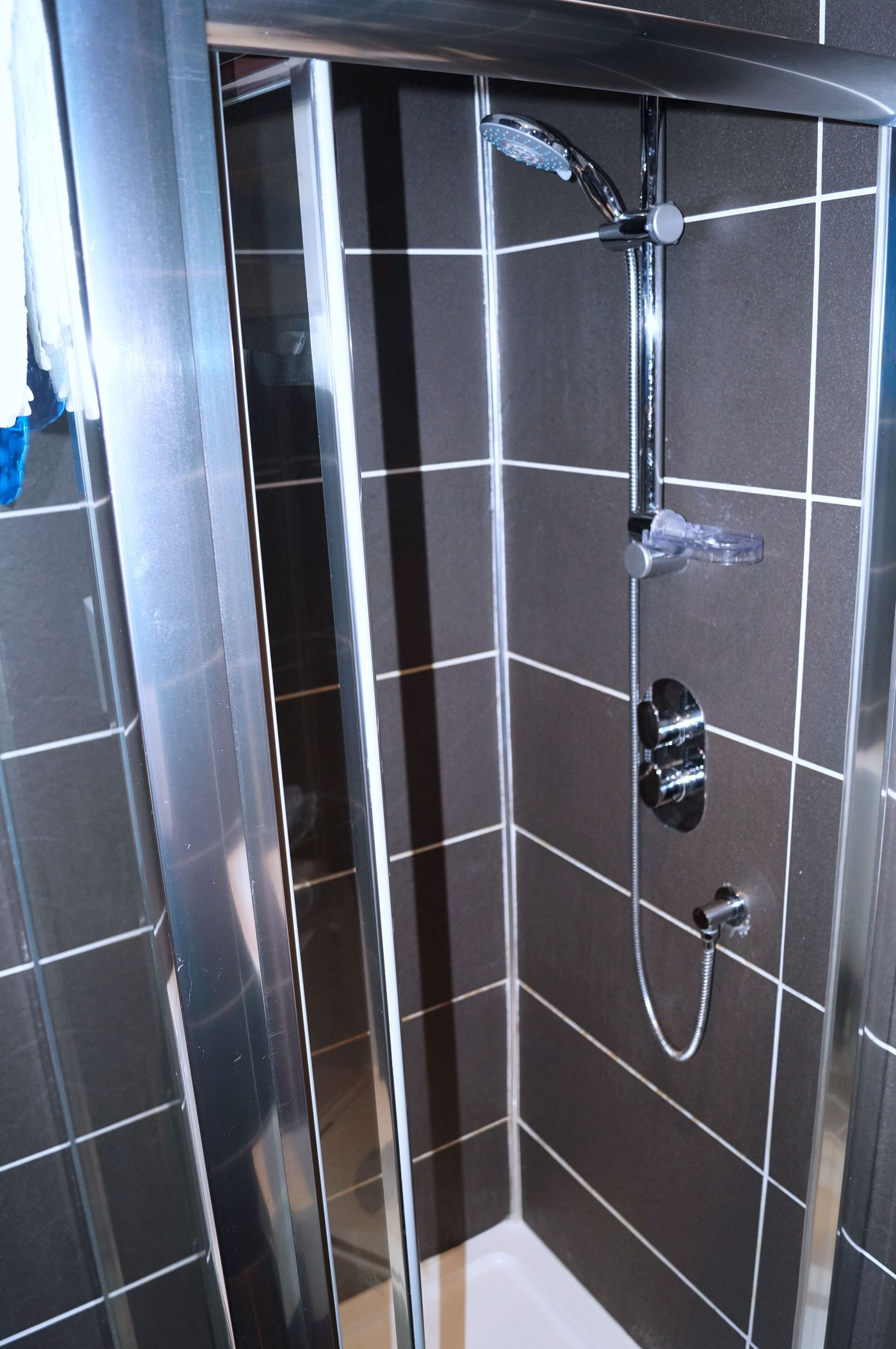 A modern shower with a handheld showerhead and a wall-mounted faucet.