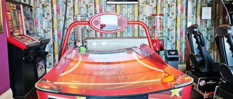 Una máquina de pinball en una habitación con una pared de diseño llamativo y un televisor montado.