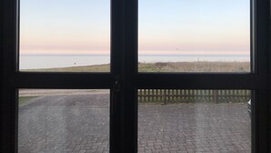 Vista a través de una ventana que muestra una zona pavimentada al frente y un campo de césped en la distancia.