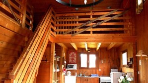L’intérieur d’un chalet en bois comprend une cuisine, un coin repas et un escalier.