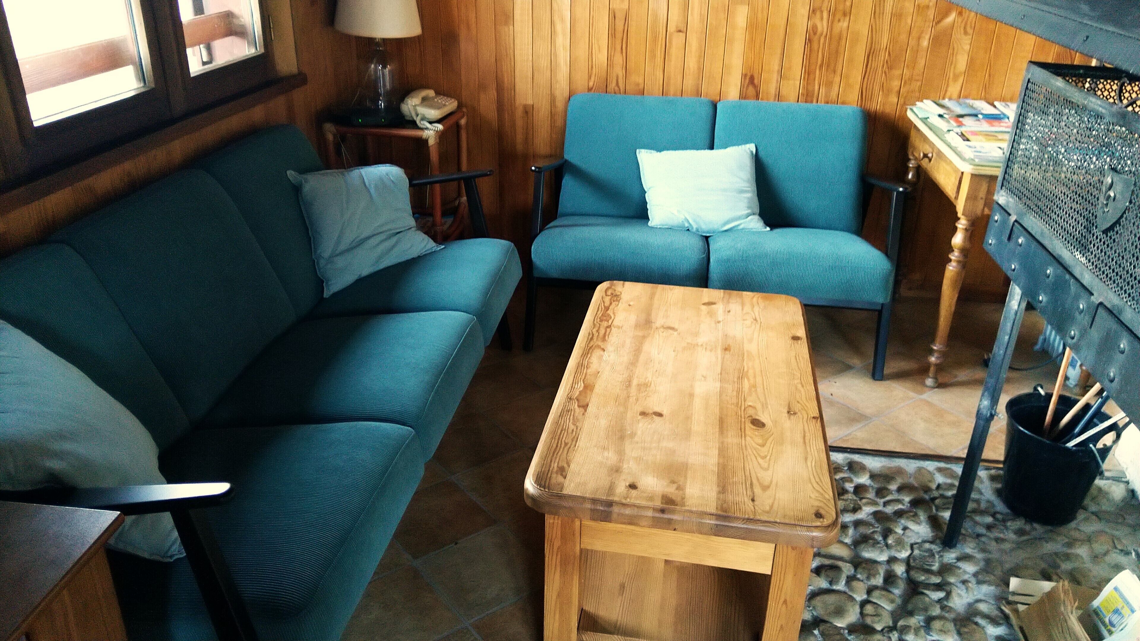 A cozy room with a blue sofa, a wooden coffee table, and a small side table with a lamp and phone.