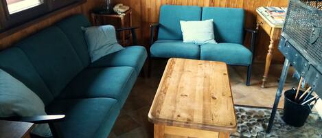 A cozy room with a blue sofa, a wooden coffee table, and a small side table with a lamp and phone.