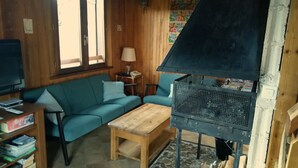 Un salon chaleureux avec un canapé bleu, une table basse en bois et un poêle à bois.