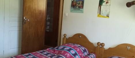 A bedroom with a wooden bed, a door, and two posters on the wall.
