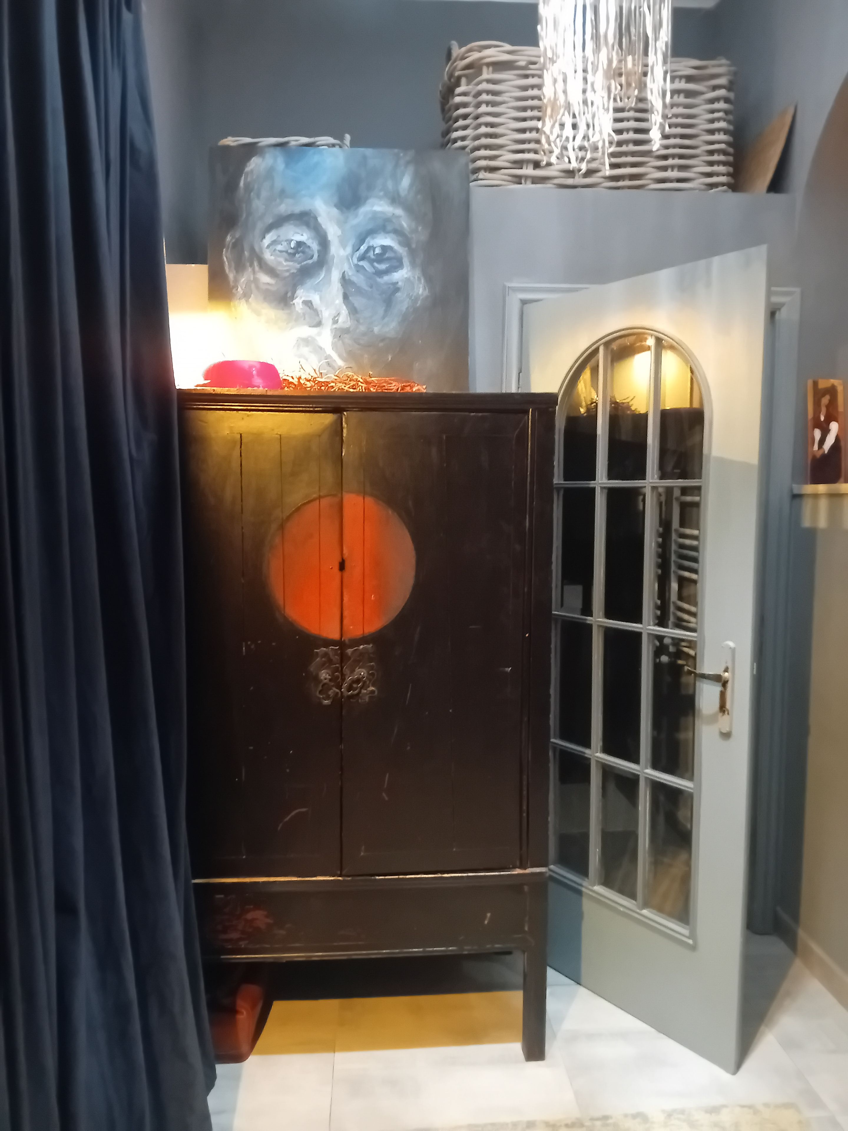 A room with a dark wooden cabinet, a large painting, and a door with a glass panel.