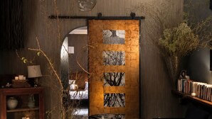 Um interior moderno com uma mesa de jantar de madeira, uma estante e um painel decorativo na parede.