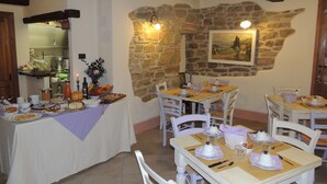 Un comedor con paredes de piedra, vigas de madera y mobiliario blanco.