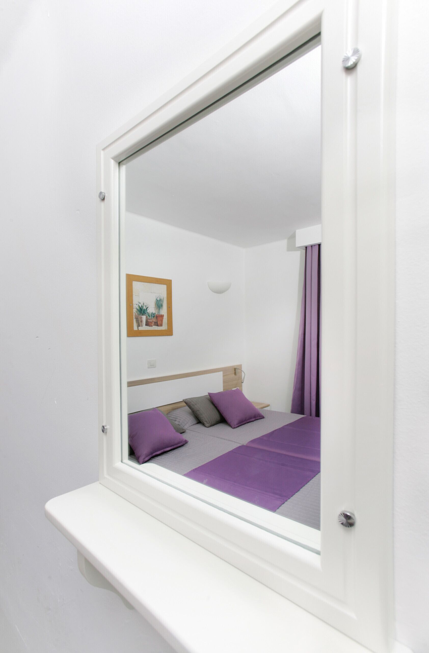 Un dormitorio con una cama, una mesita de noche, una lámpara de pared y un cuadro enmarcado.