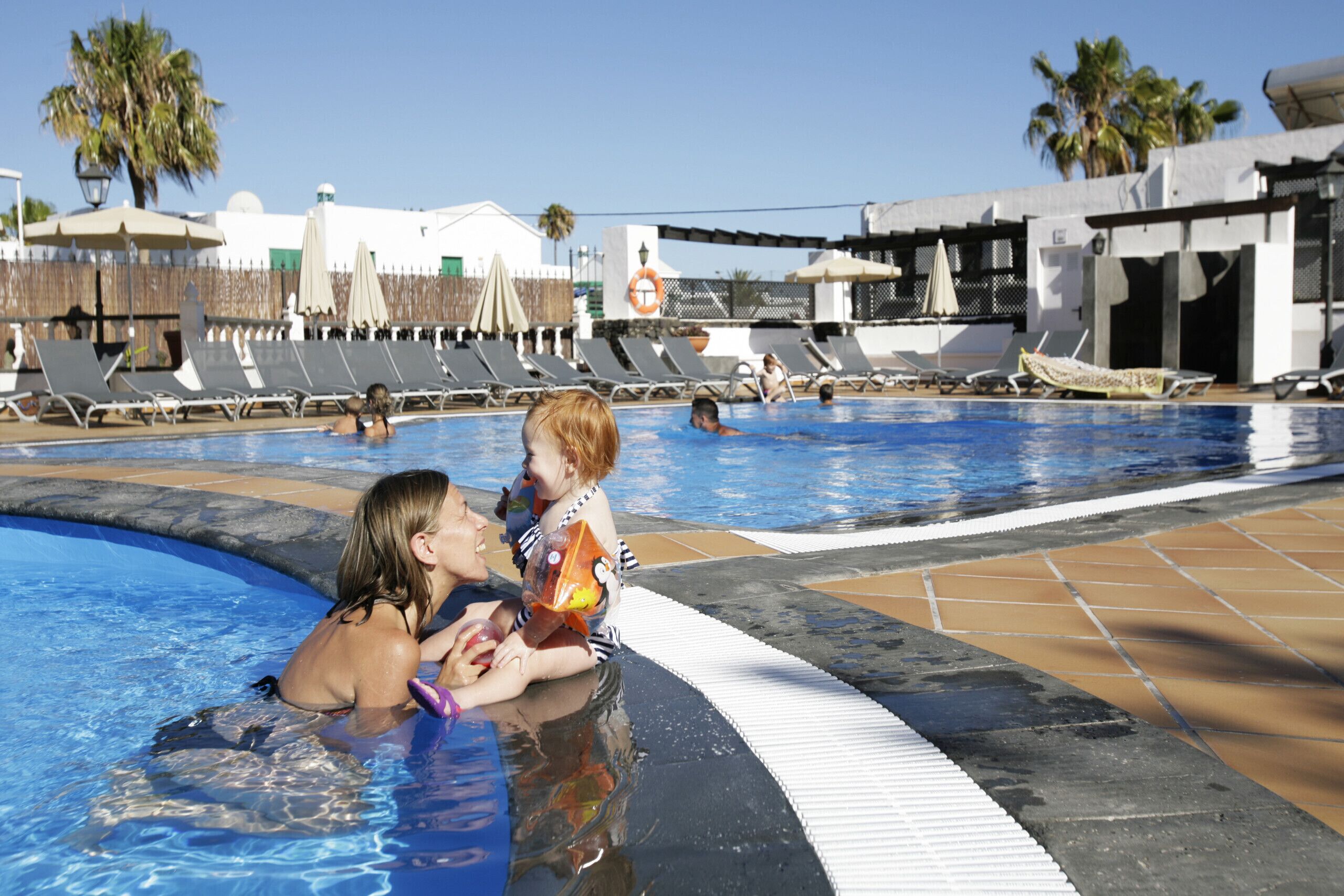 Un área de piscina con sillas de descanso y un flotador.