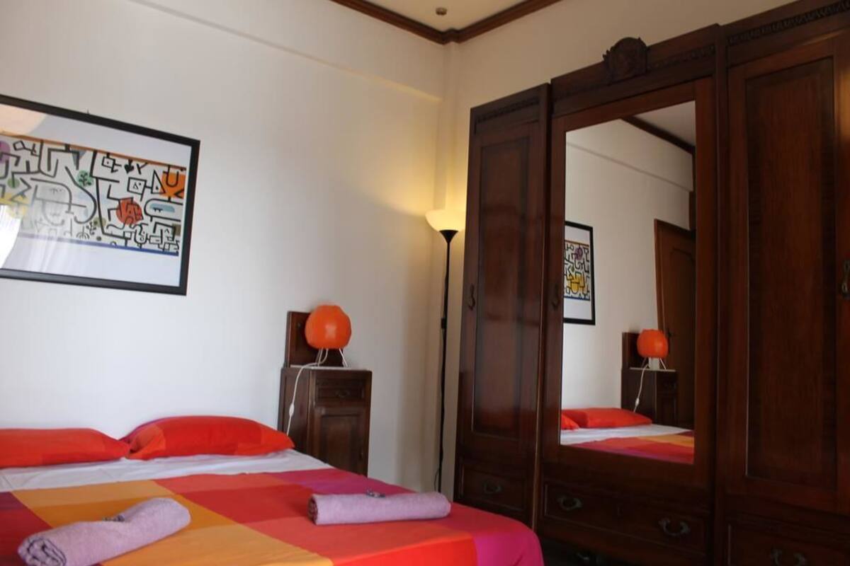 A hotel room with a bed, a large mirror, and a wall with a framed artwork.